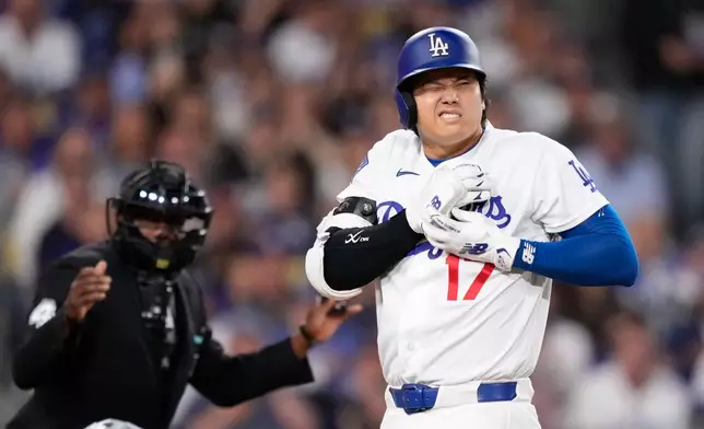 Los Angeles Dodgers' Shohei Ohtani reacts after being hit by a pitch as home plate umpire Malachi Moore watches during the fourth inning of a baseball game against the Colorado Rockies, Tuesday, May 26, 2026, in Los Angeles. (AP Photo/Mark J. Terrill)