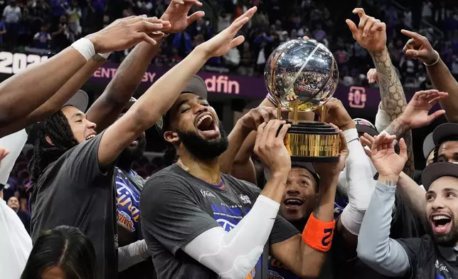 New York Knicks center Karl-Anthony Towns, center, and teammates celebrate after winning Game 4 in the Eastern Conference finals NBA basketball playoffs series against the Cleveland Cavaliers in Cleveland, Monday, May 25, 2026. (AP Photo/Sue Ogrocki)