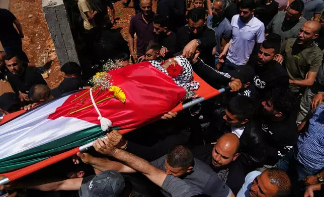 Mourners carry the body of Palestinian Zakaria Qatousa, during his funeral in the West Bank town of Deir Qaddis Wednesday, May 13, 2026. (AP Photo/Mahmoud Illean)