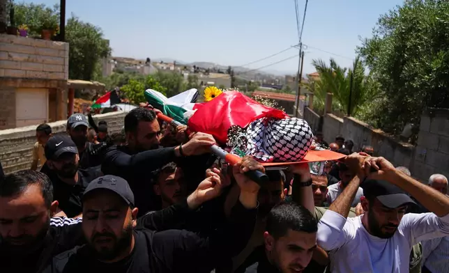 Mourners carry the body of Palestinian Zakaria Qatousa, during his funeral in the West Bank town of Deir Qaddis Wednesday, May 13, 2026. (AP Photo/Mahmoud Illean)