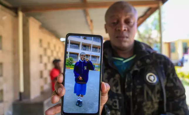 John Muiruri, father of Nicole Muiruri, who died in the fire at Utumishi Girls Academy, shows a photo of his daughter as he waits for body identification and DNA testing at Naivasha Funeral Home in Naivasha Town, Rift Valley region, Kenya, Friday, May 29, 2026. (AP Photo/Andrew Kasuku)