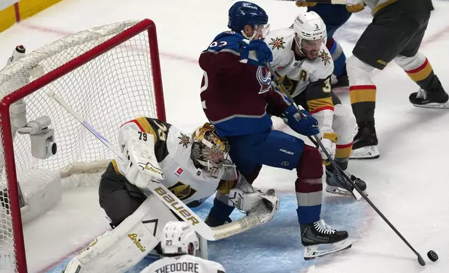 Vegas Golden Knights defenseman Brayden McNabb, back, struggles to control the puck as goaltender Carter Hart, front, runs into Colorado Avalanche left wing Gabriel Landeskog during the first period in Game 1 of the Western Conference finals NHL hockey Stanley Cup playoff series Wednesday, May 20, 2026, in Denver. (AP Photo/David Zalubowski)