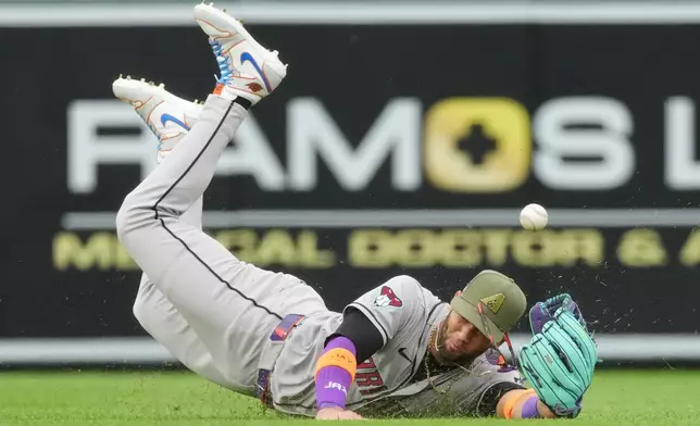 Arizona Diamondbacks left fielder Lourdes Gurriel Jr. has the ball pop out of his glove while tryig to field an RBI single off the bt of Colorado Rockies' Mickey Moniak in the first inning of a baseball game Saturday, May 16, 2026, in Denver. (AP Photo/David Zalubowski)