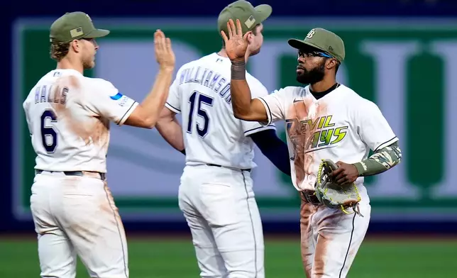 Tampa Bay Rays center fielder Cedric Mullins celebrates with shortstop Taylor Walls (6) and second baseman Ben Williamson (15) after the team defeated the Miami Marlins during a baseball game Friday, May 15, 2026, in St. Petersburg, Fla. (AP Photo/Chris O'Meara)