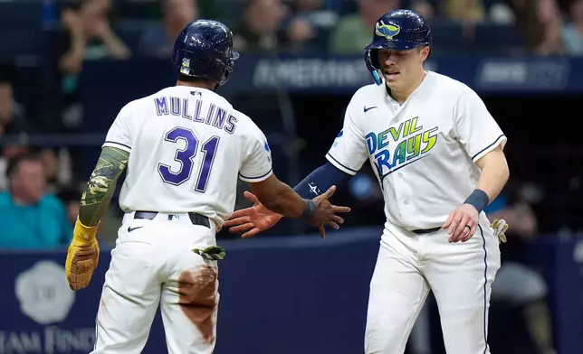 Tampa Bay Rays' Cedric Mullins (31) and Hunter Feduccia celebrate after scoring on a two-run double by Taylor Walls pff Miami Marlins pitcher Janson Junk during the fourth inning of a baseball game Friday, May 15, 2026, in St. Petersburg, Fla. (AP Photo/Chris O'Meara)