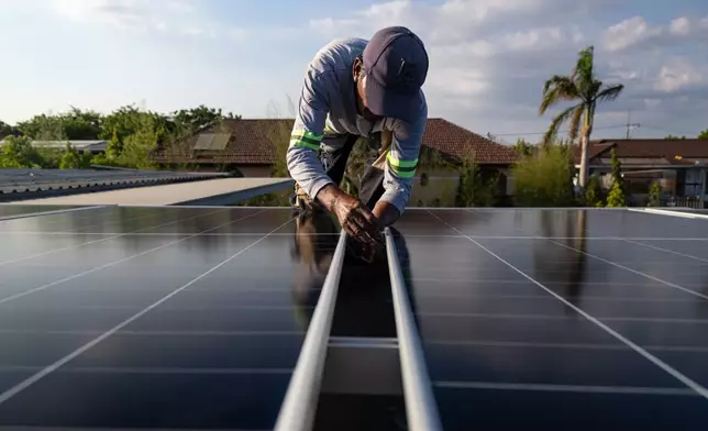 A solar installer secures a solar panel onto the roof of a home in Manila, Philippines, on April 30, 2026. (AP Photo/Anton L. Delgado)