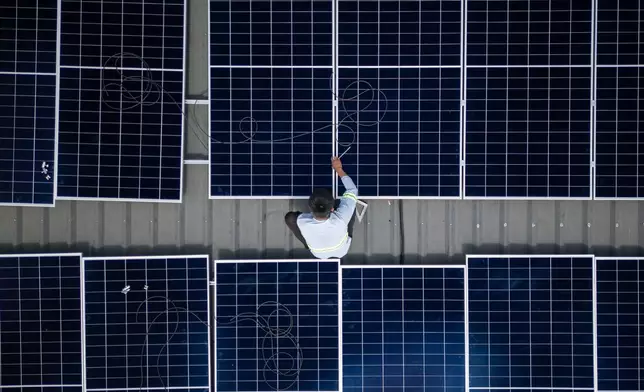 A solar installer secures a solar panel onto the roof of a home in Manila, Philippines, on May 1, 2026. (AP Photo/Anton L. Delgado)