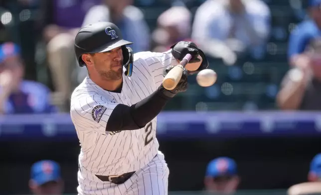 Colorado Rockies' Tyler Freeman puts down a bunt single against New York Mets starting pitcher Christian Scott in the fourth inning of a baseball game Thursday, May 7, 2026, in Denver. (AP Photo/David Zalubowski)