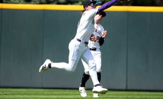 Colorado Rockies center fielder Jake McCarthy, front, cuts off right fielder Troy Johnston to pull in a fly ball off the bat of New York Mets second baseman Marcus Semien in the sixth inning of a baseball game Thursday, May 7, 2026, in Denver. (AP Photo/David Zalubowski)