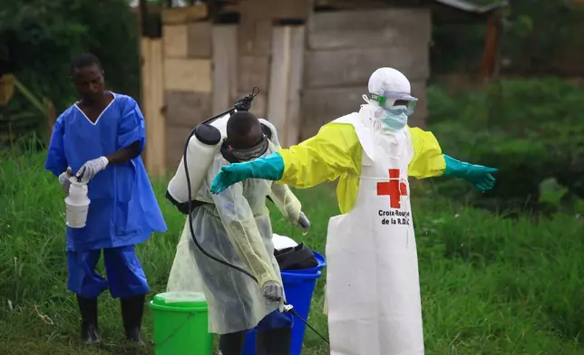 FILE - A health worker sprays disinfectant on his colleague after working at an Ebola treatment center in Beni, eastern Congo, Sept 9, 2018. (AP Photo/Al-hadji Kudra Maliro, File)