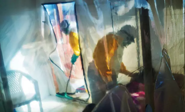 FILE - Health workers wearing protective suits tend to an Ebola victim kept in an isolation tent in Beni, Congo, July 13, 2019. (AP Photo/Jerome Delay, File)