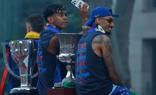FC Barcelona players Lamine Yamal, left, and Raphinha celebrate atop a bus after winning the Spanish La Liga title in Barcelona, Spain, Monday, May 11, 2026. (AP Photo/Joan Monfort)