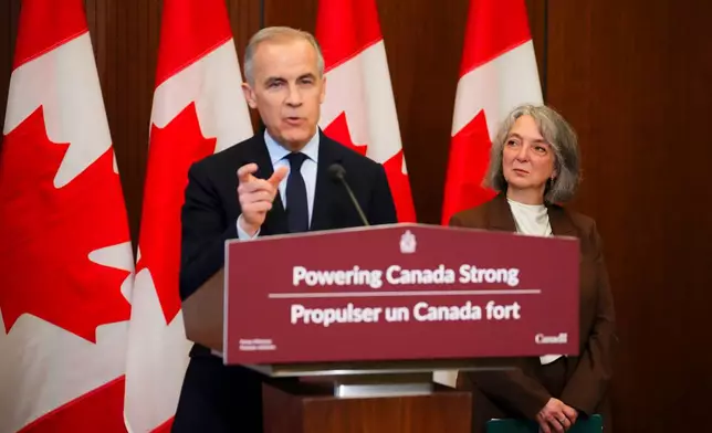 Prime Minister Mark Carney makes an announcement accompanied by Minister of Environment and Climate Change Julie Dabrusin, right, on Parliament Hill in Ottawa on Thursday, May 14, 2026. (Sean Kilpatrick/The Canadian Press via AP)