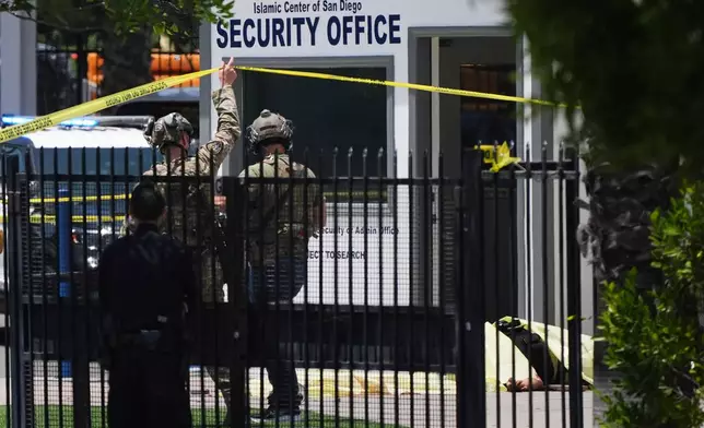 A body is covered with a tarp at the scene of a shooting outside the Islamic Center of San Diego Monday, May 18, 2026, in San Diego. (AP Photo/Gregory Bull)