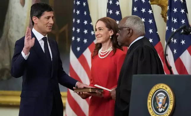 Supreme Court Justice Clarence Thomas administers the oath during the swearing in of Kevin Warsh, left, as Chairman of the Federal Reserve in the East Room of the White House, Friday, May 22, 2026, in Washington, as Warsh's wife Jane Lauder, looks on. (AP Photo/Manuel Balce Ceneta)