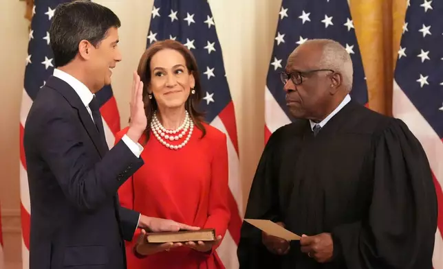 Justice Clarence Thomas, right, administers the oath during the swearing in of Kevin Warsh as Chairman of the Federal Reserve, left, as Warsh's wife Jane Lauder looks on, in the East Room of the White House, Friday, May 22, 2026, in Washington. (AP Photo/Alex Brandon)