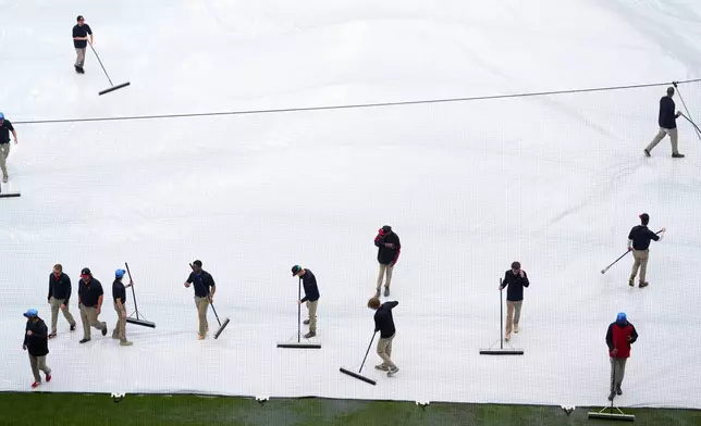 Grounds crew removes water from the tarp in a rain-delayed second inning of a baseball game between the Atlanta Braves and the Washington Nationals, Saturday, May 23, 2026, in Atlanta. (AP Photo/Mike Stewart)