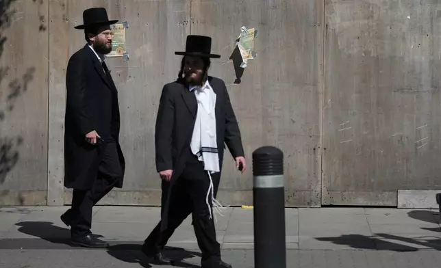 Two men walk in London, Thursday, April 30, 2026, near the scene where two people were recently stabbed in the Golders Green neighbourhood, that has a large Jewish community. (AP Photo/Alastair Grant)
