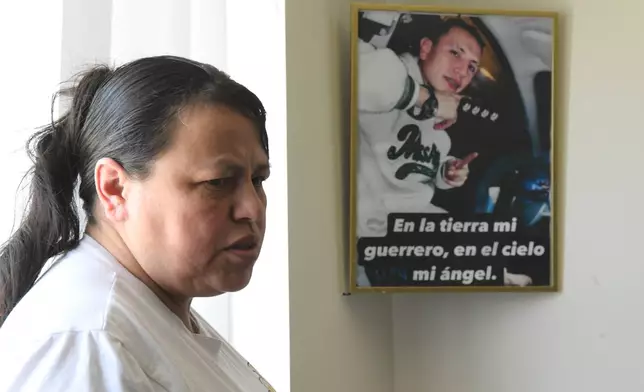Adriana Garzon, mother of Brayan Rayo Garzon who died by suicide while in ICE custody in April 2025, stands next to a photo of Rayo that reads "On earth, my warrior; in heaven, my angel" in Spanish in Garzon's home in St. Louis, Friday, May 1, 2026. (AP Photo/Nick Ingram)