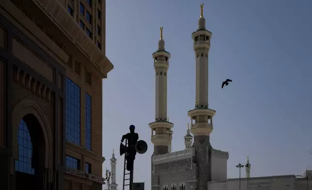 A worker is silhouetted as he cleans a speaker outside the Grand Mosque, during the annual Hajj pilgrimage in the Muslim holy city of Mecca, Saudi Arabia, Friday, May 22, 2026. (AP Photo/Altaf Qadri)