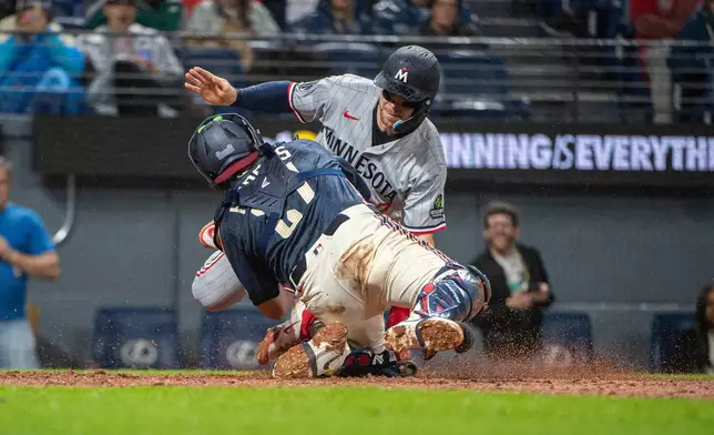 Minnesota Twins' Ryan Jeffers, top, is tagged out by Cleveland Guardians' Austin Hedges, front, at home plate during the sixth inning of a baseball game, Friday, May 8, 2026, in Cleveland. (AP Photo/Phil Long)