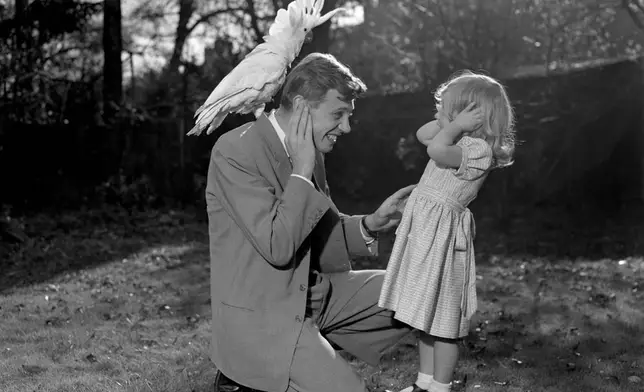 FILE - Three year old Susan and her father David Attenborough pose for a photo with a sulphur-crested cockatoo Georgie, Dec. 7, 1957. (PA via AP)