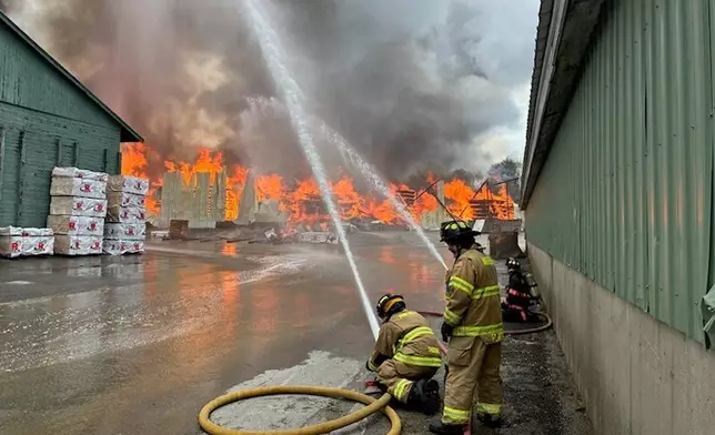 This photo provided by the Maine Department of Public Safety shows Firefighters try to extinguish flames from a large fire at Robbins Lumber in Searsmont, Maine on Friday, May 15, 2026 (Maine Department of Public Safety via AP)