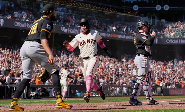 San Francisco Giants' Christian Koss, center, scores against the Pittsburgh Pirates on Willy Adames' single during the 10th inning of a baseball game Sunday, May 10, 2026, in San Francisco. (AP Photo/Godofredo A. Vásquez)