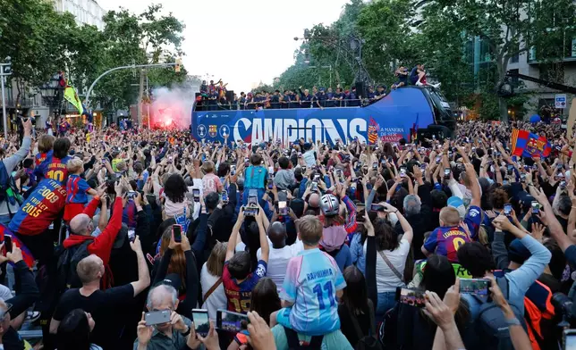 Surrounded by supporters, FC Barcelona players celebrate atop a bus after winning the Spanish La Liga title in Barcelona, Spain, Monday, May 11, 2026. (AP Photo/Joan Monfort)