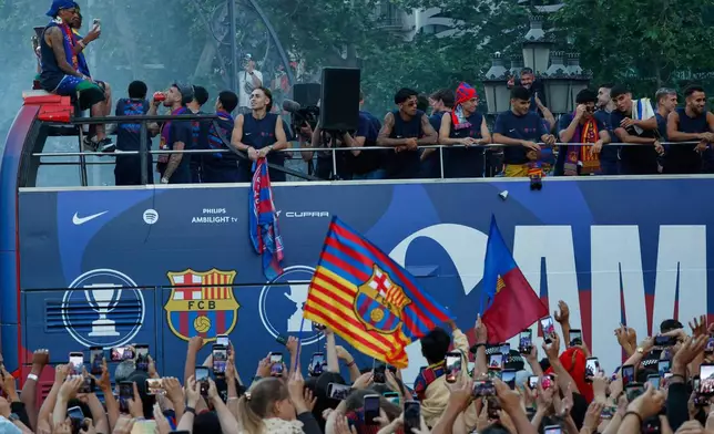 Surrounded by supporters, FC Barcelona players celebrate atop a bus after winning the Spanish La Liga title in Barcelona, Spain, Monday, May 11, 2026. (AP Photo/Joan Monfort)