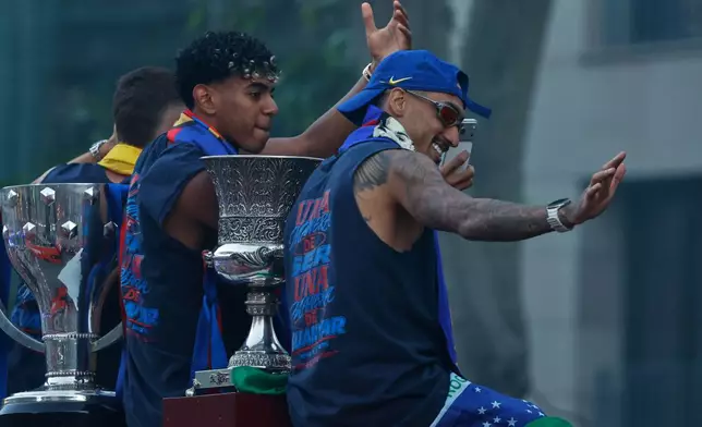FC Barcelona players Lamine Yamal, left, and Raphinha celebrate atop a bus after winning the Spanish La Liga title in Barcelona, Spain, Monday, May 11, 2026. (AP Photo/Joan Monfort)