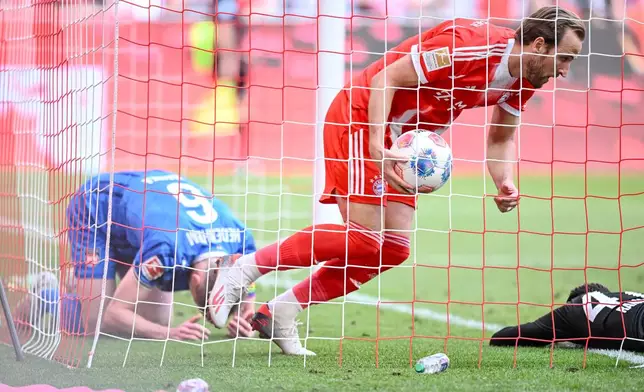 Bayern's Harry Kane retrieves the ball from the goal after the 3:3 during a German Bundesliga soccer match between Bayern Munich and 1. FC Heidenheim in Munich, Germany, Saturday, May 2, 2026. (Harry Langer/dpa via AP)