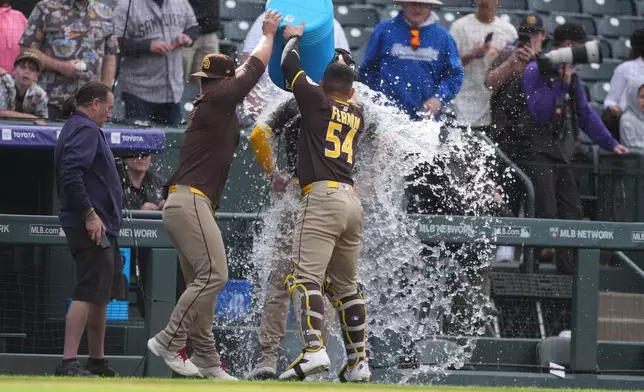 San Diego Padres first baseman Ty France, left, and catcher Freddy Fermin, right, douse Gavin Sheets as he does a television interview after leading the Padres to a victory over the Colorado Rockies in a baseball game Thursday, April 23, 2026, in Denver. (AP Photo/David Zalubowski)