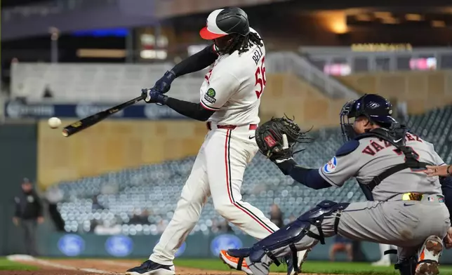 Minnesota Twins'Josh Bell, left, hits an RBI single during the sixth inning of a baseball game against the Houston Astros, Monday, May 18, 2026, in Minneapolis. (AP Photo/Abbie Parr)