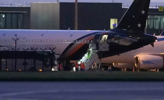 Passengers leave a plane at Manchester Airport, after being repatriated to the United Kingdom from the MV Hondius cruise ship, which was hit by hantavirus, Sunday, May 10, 2026, in Manchester, England. (Peter Byrne/PA via AP)