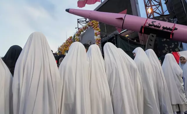 A group of girls stand beside a "Khaybar-buster" missile during a mass wedding ceremony for couples participating in the "Janfada" ("Sacrifice for Iran") pro-government campaign in Tehran, Iran, Monday, May 18, 2026. (AP Photo/Vahid Salemi)