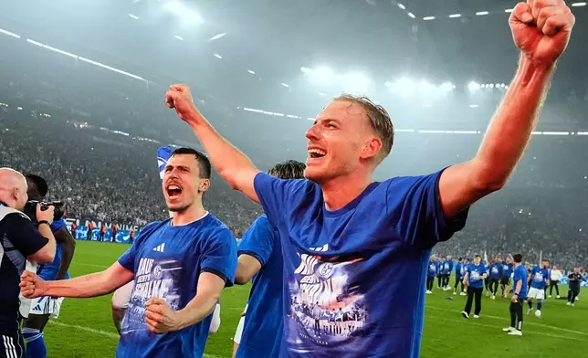Schalke's Timo Becker and Schalke's Ron Schallenberg celebrate after FC Schalke 04 secured promotion to the German Bundesliga by winning the Bundesliga 2 match against Fortuna Duesseldorf at the Arena in Gelsenkirchen, Germany, Saturday, May 2, 2026. (AP Photo/Martin Meissner)
