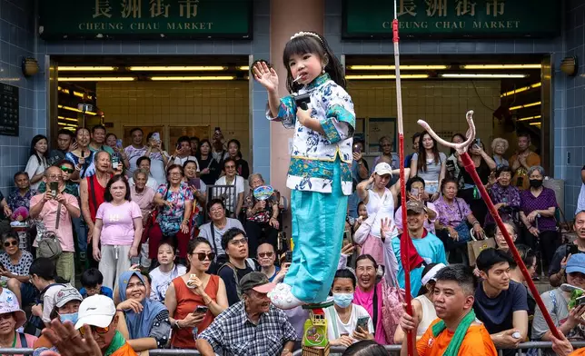 A child is hoisted up as participants take part in the Piu Sik Parade at the Bun Festival in Cheung Chau Island in Hong Kong, Sunday, May 24, 2026. (AP Photo/Chan Long Hei)