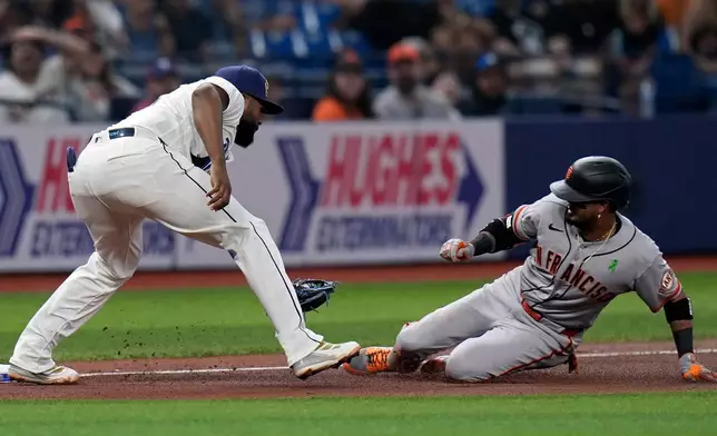 Tampa Bay Rays third baseman Junior Caminero (13) prepares to tag out San Francisco Giants' Luis Arraez at third base after Arraez tried to stretch a double into a triple during the fourth inning of a baseball game Friday, May 1, 2026, in St. Petersburg, Fla. (AP Photo/Chris O'Meara)