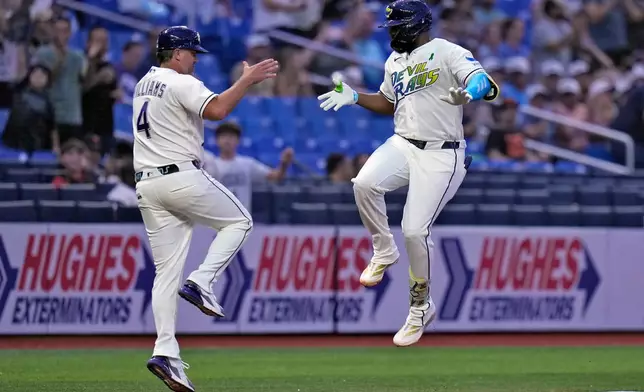 Tampa Bay Rays' Junior Caminero celebrates his solo home run off San Francisco Giants pitcher Robbie Ray with third base coach Brady Williams (4) during the fourth inning of a baseball game Friday, May 1, 2026, in St. Petersburg, Fla. (AP Photo/Chris O'Meara)