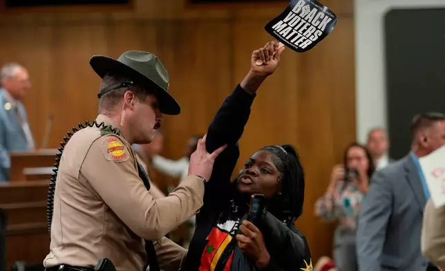 Jamiah Irby is removed by a state trooper from a Senate committee meeting during a special session of the state legislature to redraw U.S. Congressional voting maps Wednesday, May 6, 2026, in Nashville, Tenn. (AP Photo/George Walker IV)