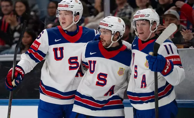 From left, USA's Mason Lohrei, Isaac Howard and Oliver Moore celebrate after their team's second goal, during the 2026 IIHF Men's Ice Hockey World Championship preliminary round group A game between Britain and the United States, in Zurich, Switzerland, Sunday, May 17, 2026. (Claudio Thoma/Keystone via AP)