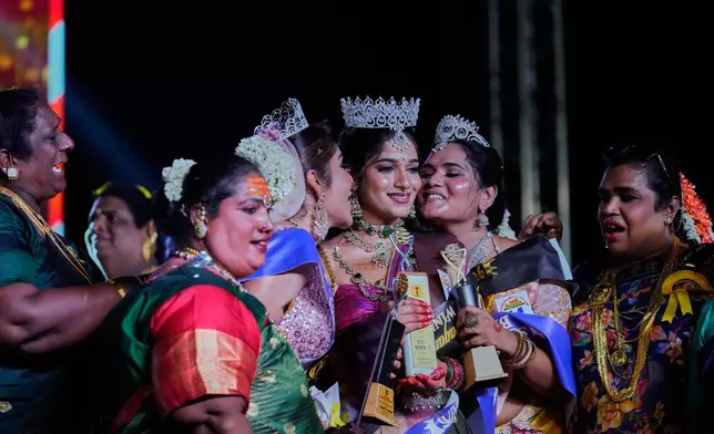 Surya Kutty, center, winner of Miss Koovagam 2026 is congratulated by other contestants during a fashion show in Villupuram, India, Monday, April 27, 2026. (AP Photo/Mahesh Kumar A.)