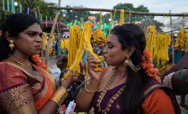 Transgender women kiss sacred threads before buying during the Koovagam festival in Kallakurichi district, in the southern Indian state of Tamil Nadu, Tuesday, April 28, 2026. (AP Photo/Mahesh Kumar A.)
