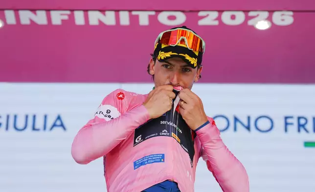 Italy's Giulio Ciccone kisses the pink jersey of the race overall leader on the podium after completing the 4th stage of the Giro d'Italia cycling race, from Catanzaro to Cosenza, Italy, Tuesday, May 12, 2026. (Gian Mattia d'Alberto/LaPresse via AP)