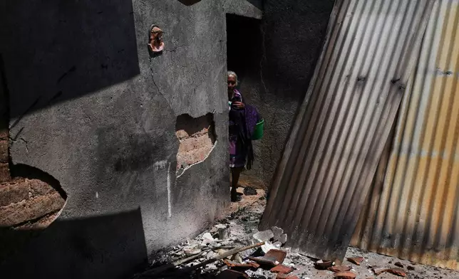 Anastasia Cabrera walks through the ruins of her home after armed attacks by local criminal groups forced dozens of residents to flee, in Tula, Mexico, Friday, May 15, 2026. (AP Photo/Marco Ugarte)