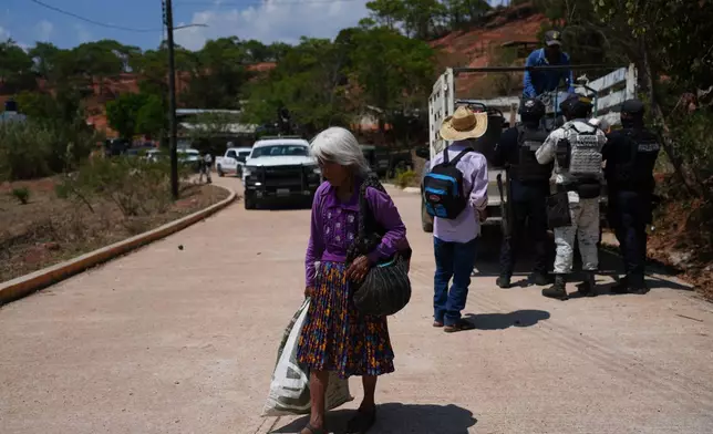 A resident walks along a street after armed attacks by local criminal groups forced more than dozens of residents to flee, in Tula, Mexico, Friday, May 15, 2026. (AP Photo/Marco Ugarte)
