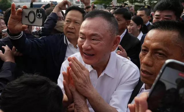 Former Thailand Prime Minister Thaksin Shinawatra, center, gestures to his supporters following his release on parole from a Bangkok prison in Bangkok, Thailand, Monday, May 11, 2026. (AP Photo/Sakchai Lalit)