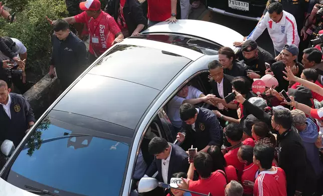 Former Thailand Prime Minister Thaksin Shinawatra shakes hands with his supporters from inside a car after he was released from a Bangkok prison in Bangkok, Thailand, Monday, May 11, 2026. (AP Photo/Sakchai Lalit)