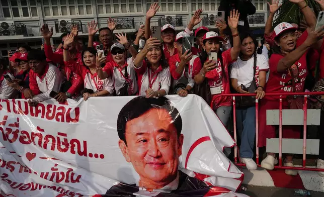 Supporters of former Thailand Prime Minister Thaksin Shinawatra wave and hold banner after he was released on parole from a Bangkok prison in Bangkok, Thailand, Monday, May 11, 2026. (AP Photo/Sakchai Lalit)